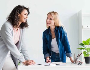 friendly female colleagues discussing work laughing office ()
